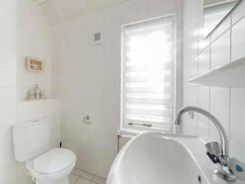 a white bathroom with a toilet and a sink at Charming Coastal Escape in Wemeldinge