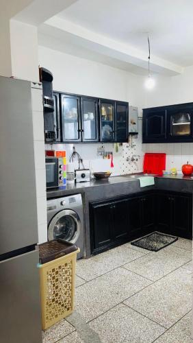 a kitchen with black cabinets and a washing machine at Apparemment al baraka in Tangier