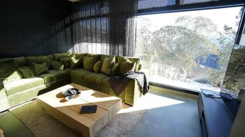 a living room with a green couch and a coffee table at Konayuki Apartment 8 in Falls Creek