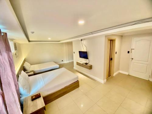 a bedroom with two beds and a television in it at Hotel Euroasia By BLUEBOOKERS in Angeles