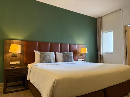 a bedroom with a large bed with a green wall at The Legacy Hotel Nana Sukhumvit, Aspira Collection in Bangkok