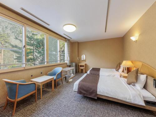 a hotel room with a bed and chairs and windows at KAMENOI HOTEL SHIOBARA Dog Friendly Hotel in Nasushiobara