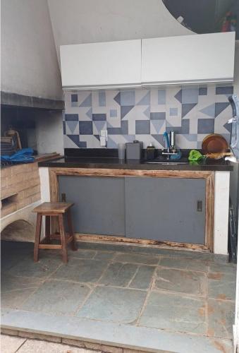 a kitchen with a counter with a sink and a stool at Suite Térrea Nova Campinas com ar e wi-fi in Campinas