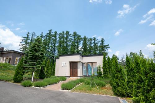 a small white house in front of trees at 冬のソナタ2 in Nakafurano
