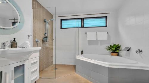 a white bathroom with a tub and a sink at Seaside Royale in Callala Beach