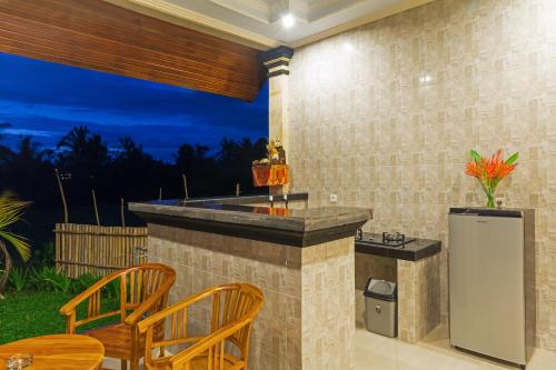a outdoor kitchen with a bar with a table and chairs at Cahaya Ubud Villa in Ubud