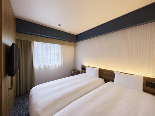 a hotel room with two beds and a window at Hotel Villa Fontaine Tokyo-Ueno Okachimachi in Tokyo