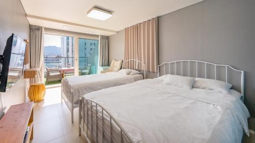 a hotel room with two beds and a balcony at Tongyeong Pension Present Pension in Tongyeong