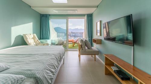 a bedroom with a bed and a flat screen tv at Tongyeong Pension Present Pension in Tongyeong