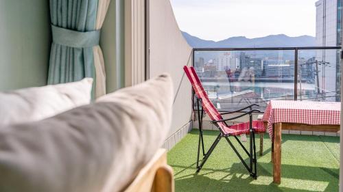 a room with a bed and a chair and a table at Tongyeong Pension Present Pension in Tongyeong