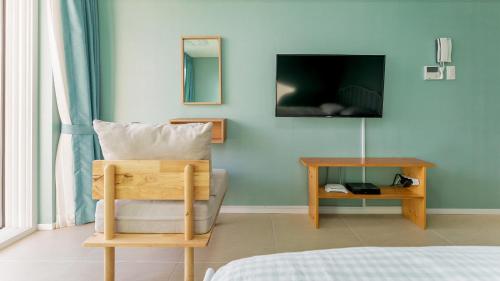 a room with a chair and a tv on a wall at Tongyeong Pension Present Pension in Tongyeong