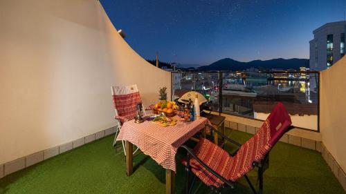 a table and chairs on a balcony with a view of a boat at Tongyeong Pension Present Pension in Tongyeong