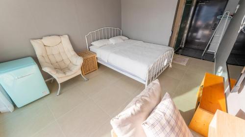 a small room with a bed and a chair at Tongyeong Pension Present Pension in Tongyeong