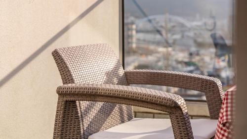 a wicker chair sitting on a balcony with a window at Tongyeong Pension Present Pension in Tongyeong