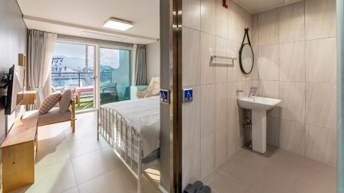 a bathroom with a bed and a sink in a room at Tongyeong Pension Present Pension in Tongyeong