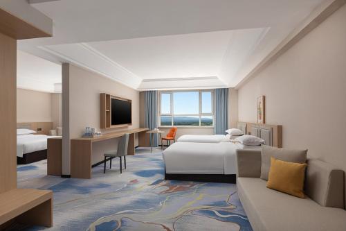 a hotel room with two beds and a desk at Days Hotel by Wyndham Xinyuan Nalati Airport in Xinyuan
