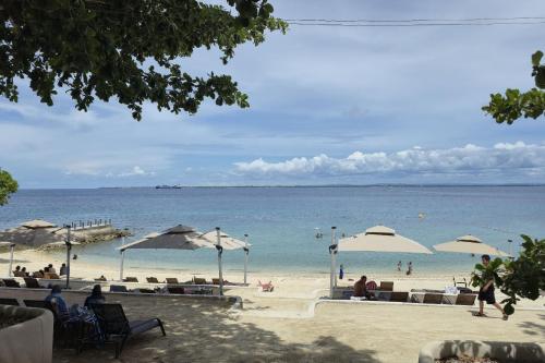 people on a beach with umbrellas and the ocean at Resort-style Comfort Near Mactan Airport in Punta Engaño