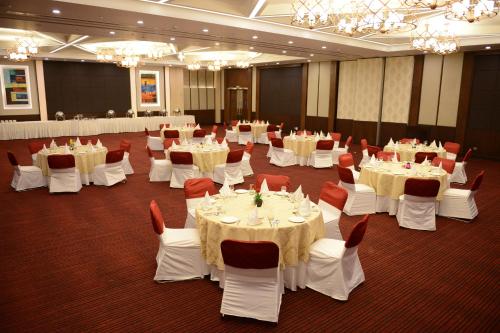 a banquet hall with white tables and red chairs at Gurmon Hotels Sohna Road Gurugram, a member of Radisson Individuals in Sohna