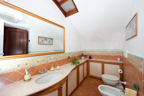 a bathroom with a sink and a toilet and a mirror at Casa Ermelinda in Amalfi