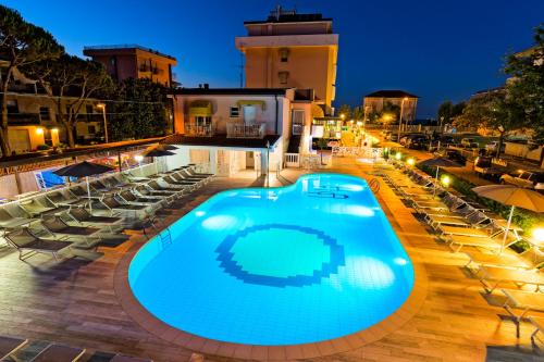 una piscina por la noche con sillas y sombrillas en Hotel Albatros, en Rímini