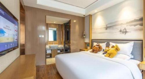 a bedroom with a large white bed with two teddy bears on it at East Queen Hotel (Xi'an Beimen Metro Station) in Xi'an