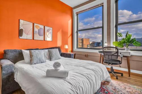 a bedroom with an orange wall with a bed and a desk at 1Br in Heart of Downtown, Sauna, Prime Location in Cleveland