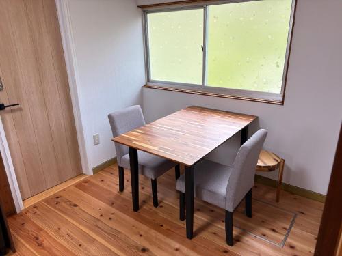 a dining room table with two chairs and a window at ゲストハウス八咫 in Tanabe