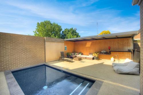 a swimming pool in front of a brick wall at Mandel on High - Echuca Holiday Homes in Echuca