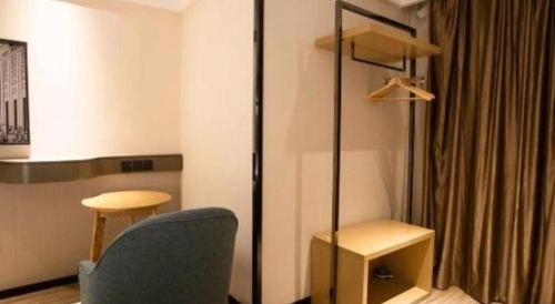 a room with a chair and a table and a desk at City Comfort Inn Beiliu Yongfeng Plaza Chengnan Bus Station in Yulin