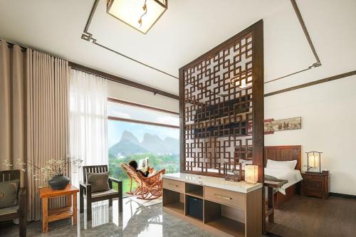 a bedroom with a desk and a large window at 阳朔归云檀邸民宿 in Yangshuo