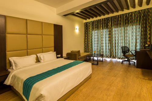 a hotel room with a large bed and a desk at Sinclairs Retreat Kalimpong in Kalimpong