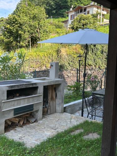 a stone fireplace with a table and an umbrella at casa vacanza l'Oleandro in Poggiridenti