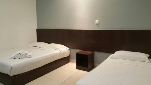 a bedroom with two beds and a nightstand and sidx sidx sidx at Tiong Nam Hotel in Pasir Gudang