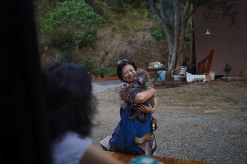 Konggu Valley Retreat Hut X By Tiny Away في T'ou-kou: امرأة ممسكة كوالا بين يديها