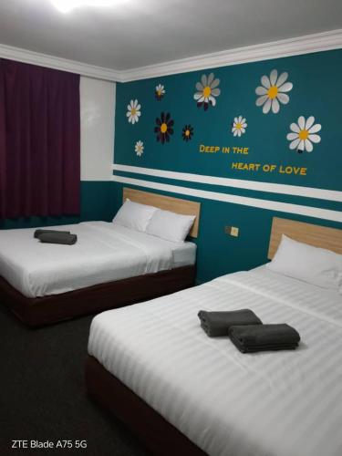 two beds in a room with flowers on the wall at Apollo hotel in Skudai