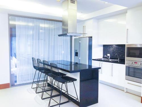 a kitchen with a black counter and chairs in it at Beachfront 120sqm 2BR with Private Plunge Pool on stunning Naithon beach in Nai Thon Beach