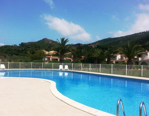 uma grande piscina azul com montanhas ao fundo em Résidence Le Village Marin em Porto-Vecchio