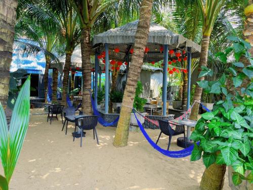 a resort with chairs and tables and palm trees at Khu Nghỉ Dưỡng Thuần Chay MIND LINK 