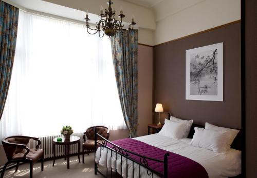 アントワープにあるホテル アントワープ ビラード パレスのベッドルーム(紫の毛布を使用した大型ベッド1台付)