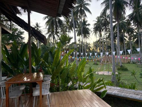 a patio with a table and chairs and a playground at บ้านพราวพร้าว Baan Proud Proud in Khanom