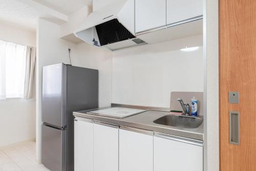a kitchen with white cabinets and a stainless steel refrigerator at -Park Higashiueno301- 4-minute walk from Ueno Station in Tokyo