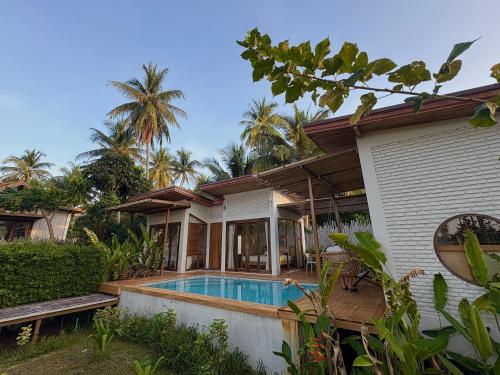 a house with a swimming pool in front of it at บ้านพราวพร้าว Baan Proud Proud in Khanom