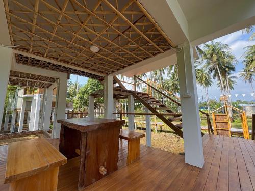 a porch with a wooden table and stairs at บ้านพราวพร้าว Baan Proud Proud in Khanom