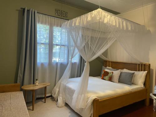 a bedroom with a canopy bed and a window at Goodtimewithfar House in Moshi