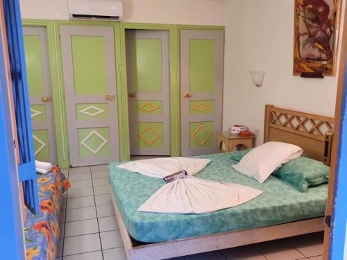 a bedroom with a bed with green and yellow cabinets at Studio à 5 min à pied de la mer in Sainte-Anne
