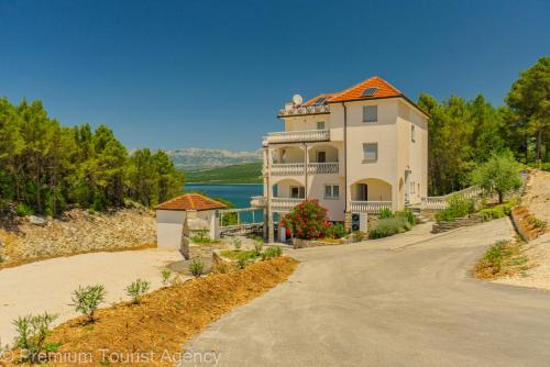 a large white building with an orange roof at Green Haven Sea & Forest Apartments in Donji Karin