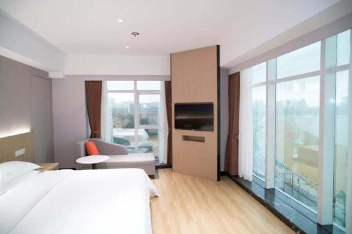 a hotel room with a bed and a large window at Grand Nest Hotel (Tang Jia Wan Beach) in Zhuhai