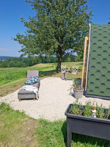 a patio with a chair and a tree in a field at Wildkraut's Kräuter- und Alpakabauernhof in Kremsmünster