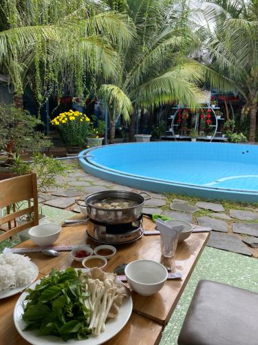 a table with plates of food next to a swimming pool at Khu Nghỉ Dưỡng Thuần Chay MIND LINK 