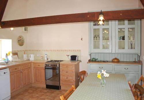 uma cozinha com uma mesa e um fogão forno superior em Old Orchard Cottage em Colyton